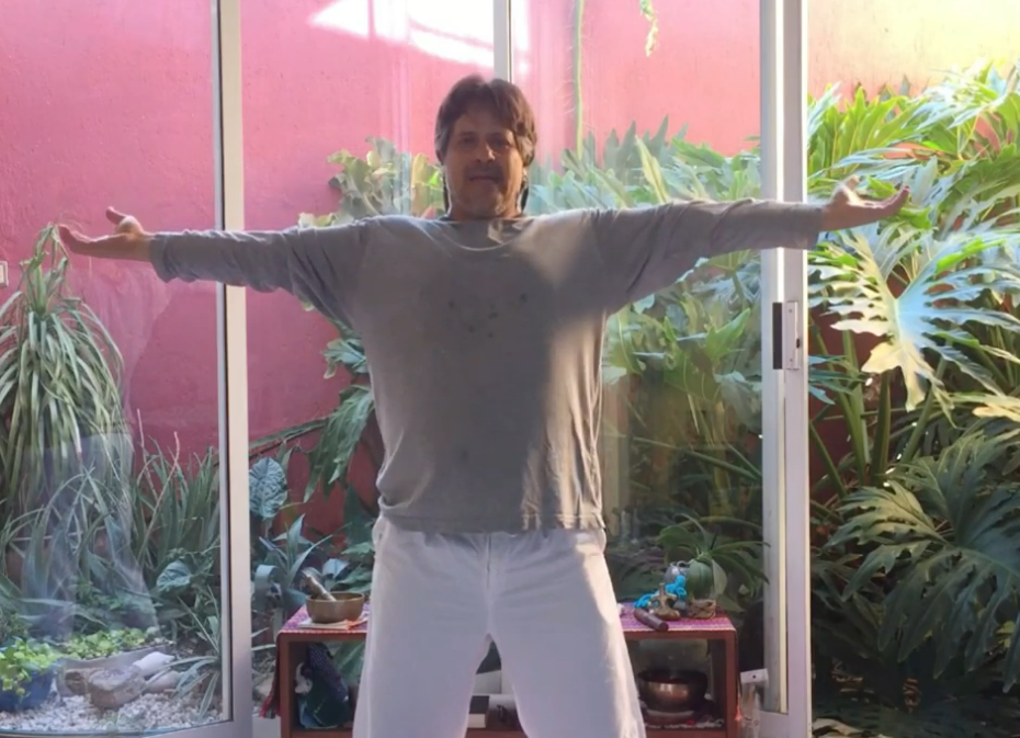 Hombre con playera gris y pantalón blanco con los brazos y piernas abiertas, haciendo ejercicio.