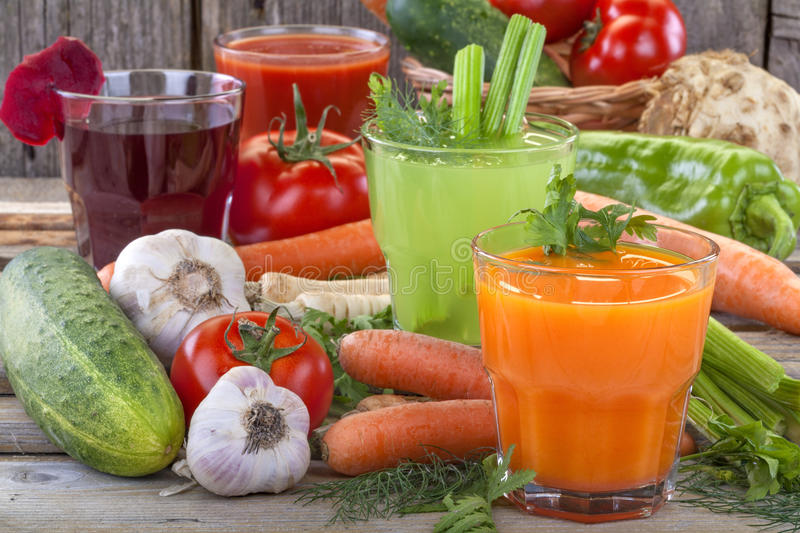 Vasos con jugos de zanahoria, apio, jitomate y betabel rodeado de esas mismas verduras